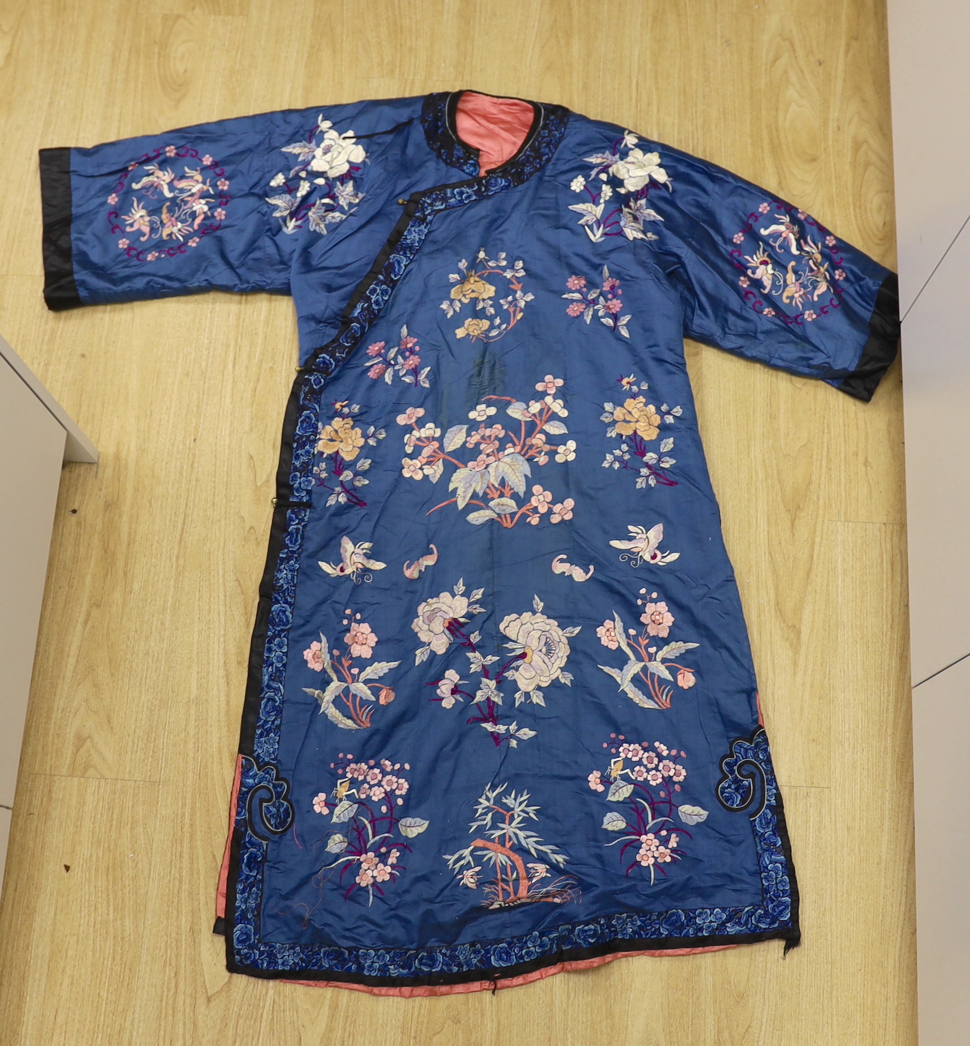 An early 20th century Chinese blue silk embroidered robe, later altered, cut and re-lined, together with various pieces of later Chinese embroidery and an earlier red silk panel with cut velvet circular motifs